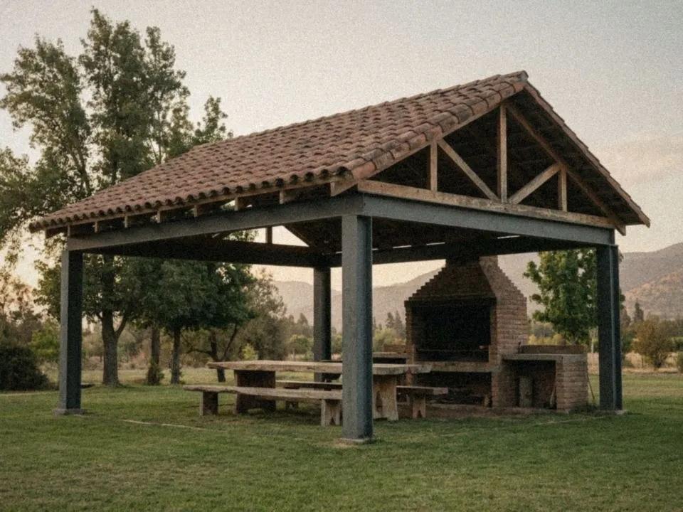 Quincho con estructura de acero, techo de tejas y parrilla de ladrillo